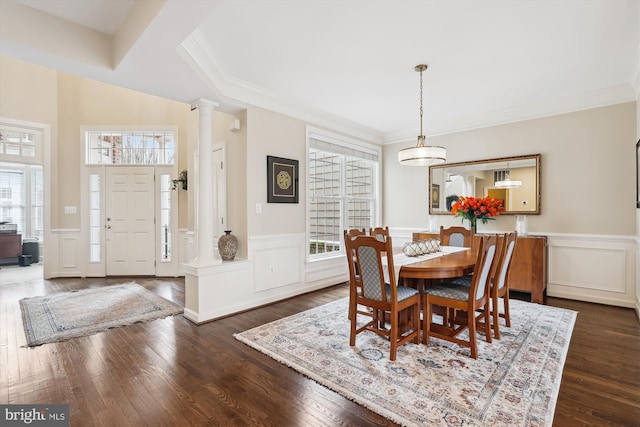 dining space with decorative columns, dark wood-type flooring, a wainscoted wall, and crown molding