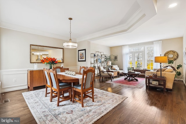 dining area with dark wood finished floors, crown molding, and a wainscoted wall