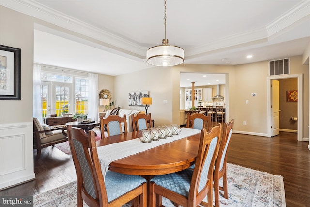 dining area featuring dark wood finished floors, visible vents, a tray ceiling, and ornamental molding