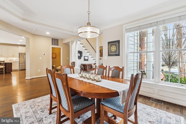 dining area featuring a wealth of natural light, visible vents, stairs, and wood finished floors