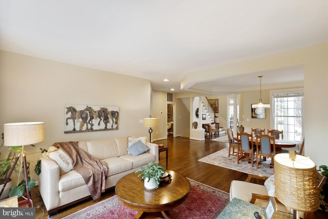 living room with stairway, dark wood-style floors, visible vents, baseboards, and recessed lighting