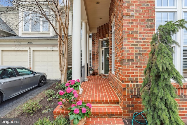 entrance to property featuring aphalt driveway, brick siding, and a garage