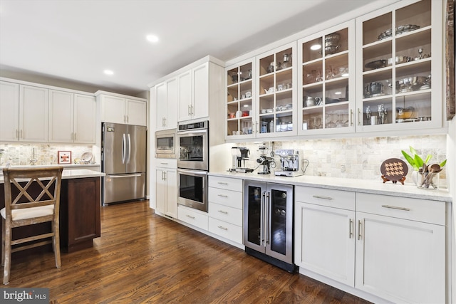 kitchen with backsplash, beverage cooler, stainless steel appliances, dark wood-style floors, and white cabinetry