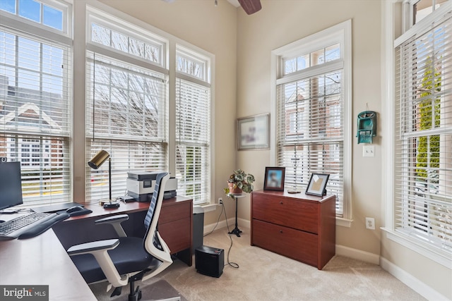 carpeted home office featuring baseboards and a ceiling fan