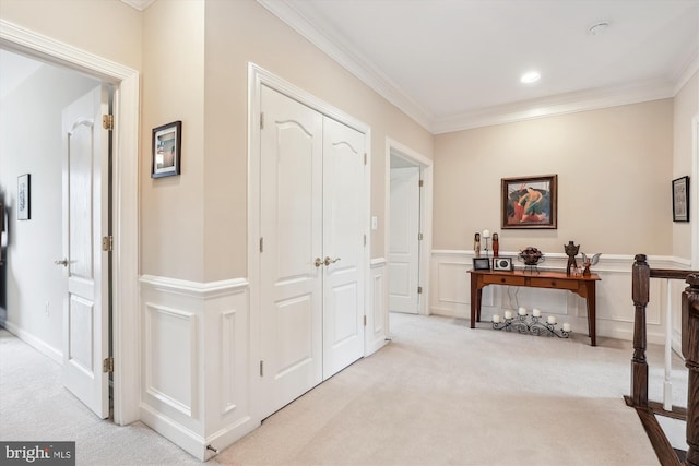 hall with light colored carpet, crown molding, and a decorative wall