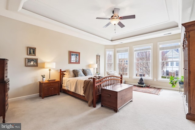 bedroom featuring baseboards, a raised ceiling, and light carpet