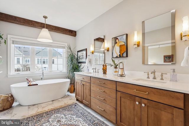 bathroom with double vanity, marble finish floor, a freestanding tub, and a sink