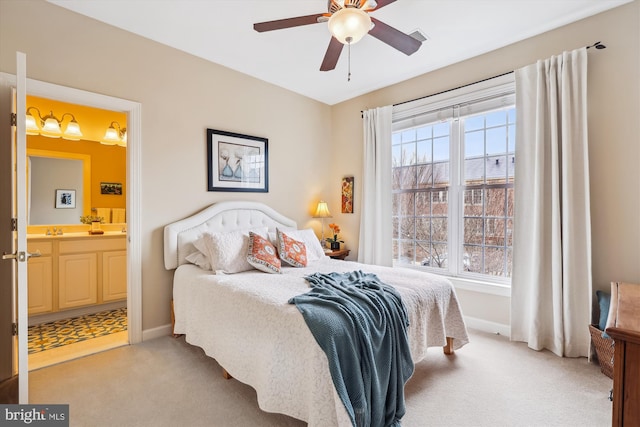 bedroom with light carpet, multiple windows, ensuite bathroom, and baseboards