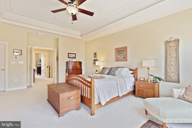 bedroom with a tray ceiling, crown molding, baseboards, light colored carpet, and ceiling fan