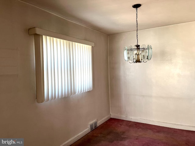 unfurnished dining area with dark colored carpet and a notable chandelier