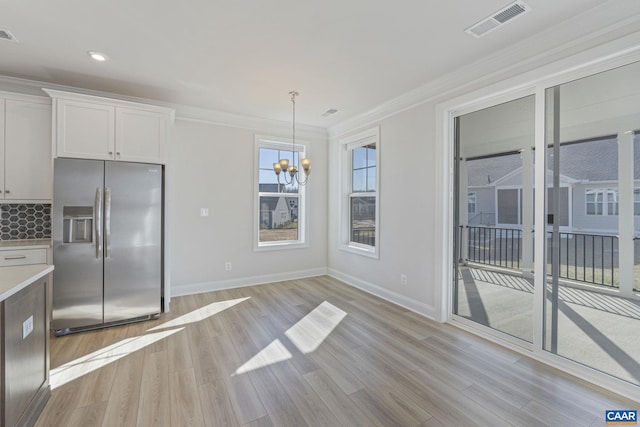 kitchen featuring pendant lighting, white cabinetry, ornamental molding, light hardwood / wood-style floors, and stainless steel fridge with ice dispenser