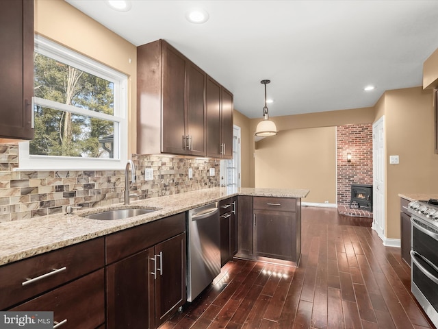 kitchen with sink, decorative light fixtures, appliances with stainless steel finishes, kitchen peninsula, and backsplash