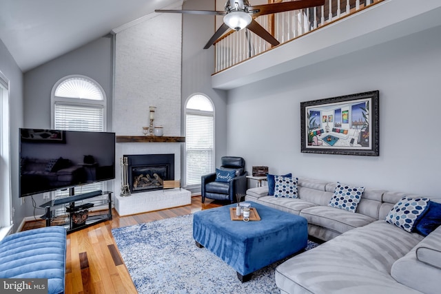 living room featuring hardwood / wood-style flooring, ceiling fan, a fireplace, and high vaulted ceiling