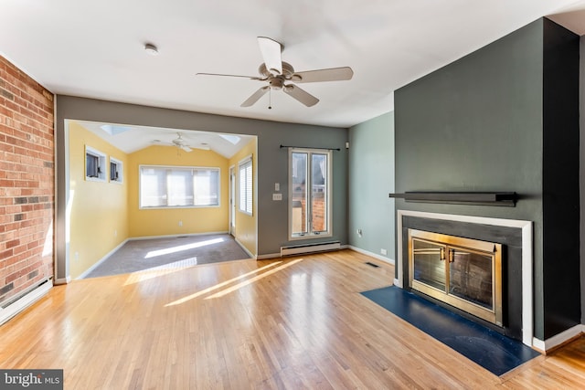 unfurnished living room with vaulted ceiling, a baseboard heating unit, and light hardwood / wood-style flooring