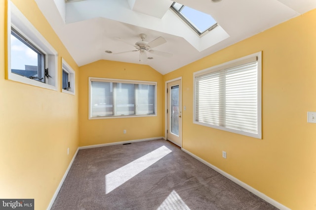 unfurnished room featuring carpet, vaulted ceiling with skylight, and ceiling fan