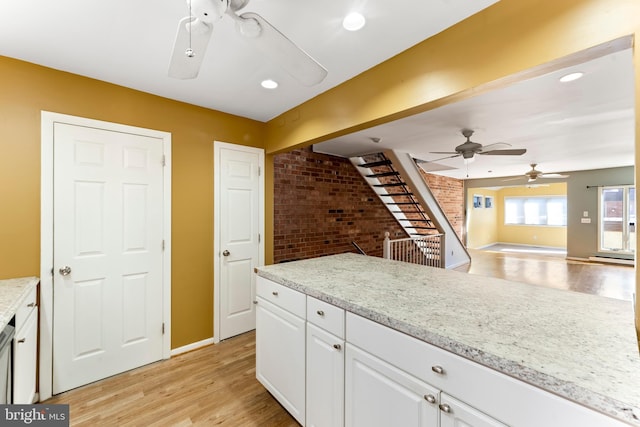 kitchen with brick wall, ceiling fan, white cabinets, and light hardwood / wood-style floors