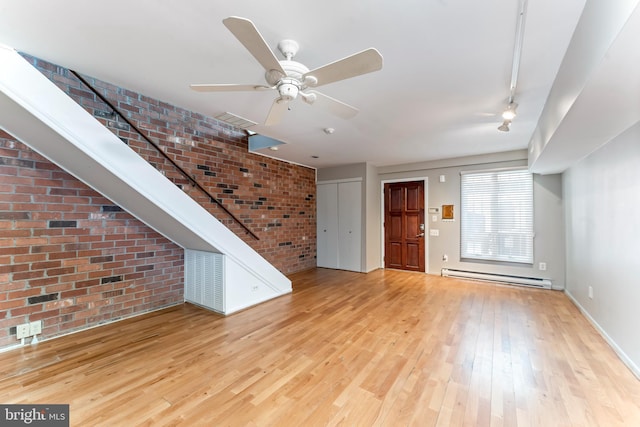 interior space featuring brick wall, rail lighting, ceiling fan, baseboard heating, and light hardwood / wood-style floors