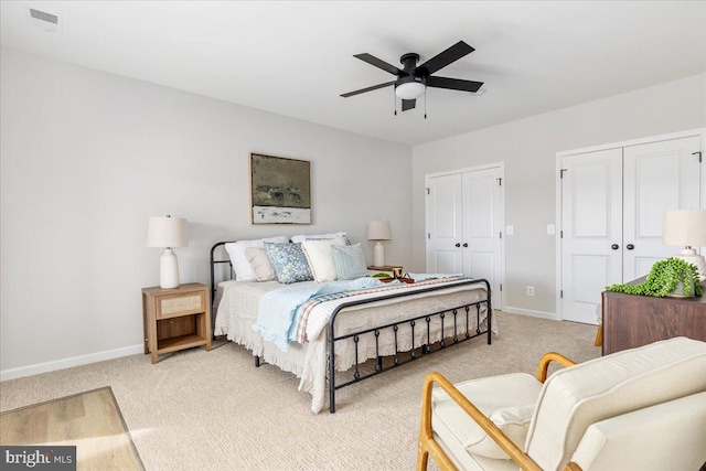 carpeted bedroom featuring multiple closets and ceiling fan