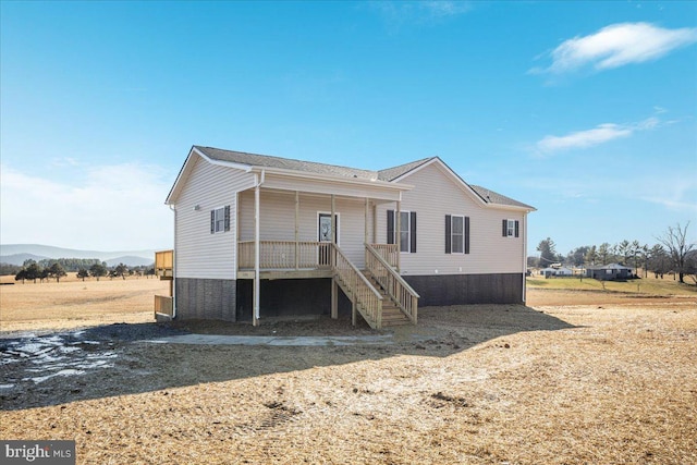 back of property featuring a mountain view and covered porch