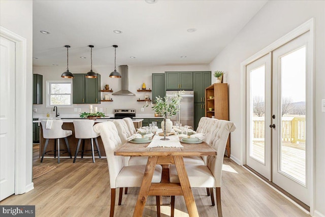 dining room with sink, light hardwood / wood-style flooring, and french doors