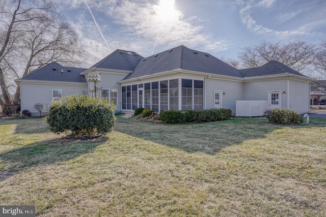 rear view of house with a sunroom and a lawn