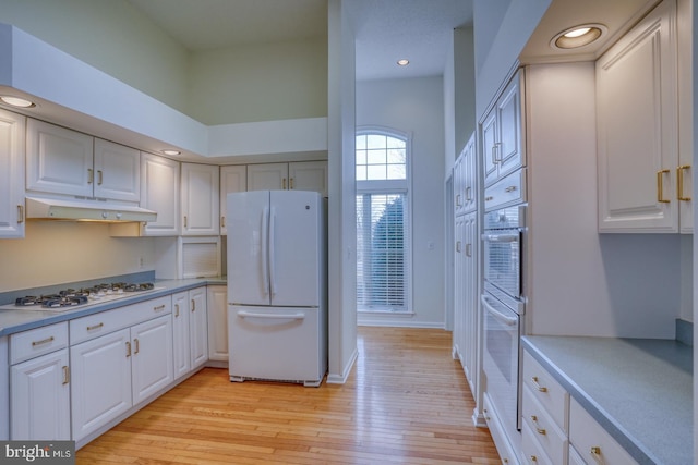 kitchen featuring white cabinetry, white appliances, a high ceiling, and light wood-type flooring