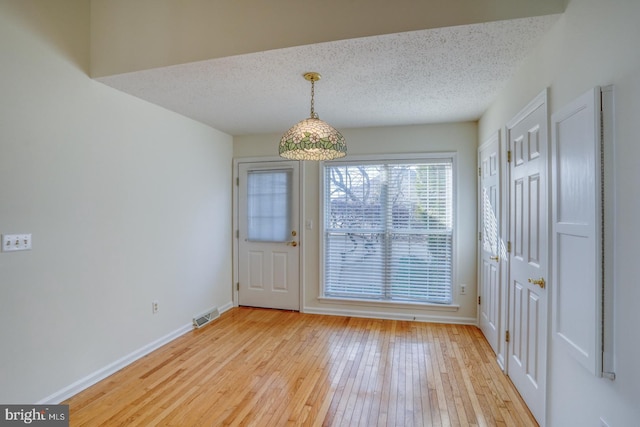 doorway to outside featuring a textured ceiling and light wood-type flooring