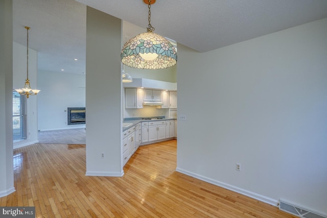 unfurnished dining area with a high ceiling, a notable chandelier, and light hardwood / wood-style flooring