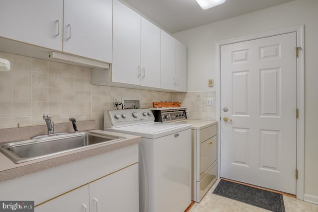 clothes washing area featuring cabinets, washing machine and dryer, and sink