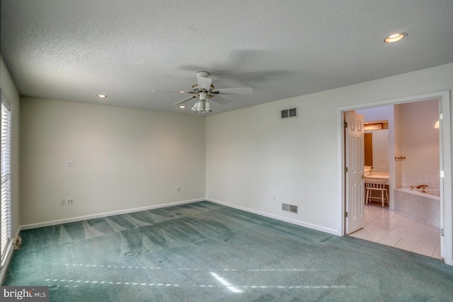 carpeted spare room featuring ceiling fan and a textured ceiling