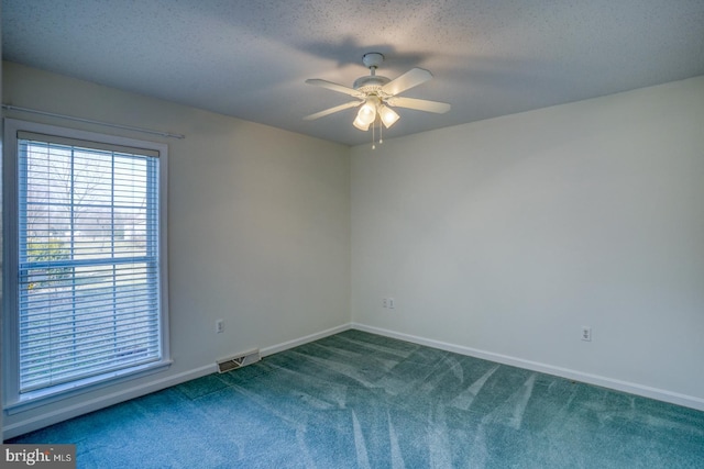 carpeted spare room with ceiling fan and a textured ceiling