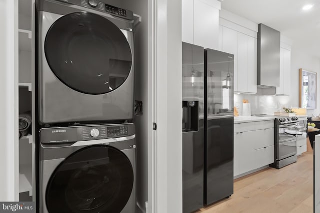 laundry room with light hardwood / wood-style floors and stacked washer / dryer