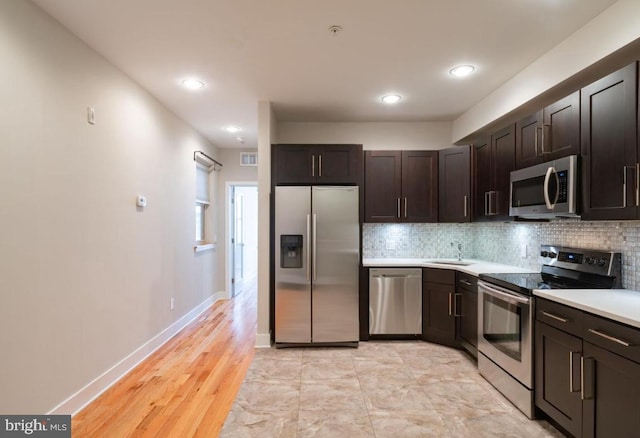 kitchen with dark brown cabinetry, backsplash, sink, and appliances with stainless steel finishes