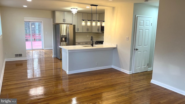 kitchen with pendant lighting, sink, dark hardwood / wood-style flooring, stainless steel fridge with ice dispenser, and kitchen peninsula