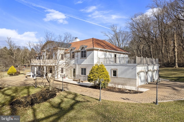 back of property with a balcony, a yard, and a patio