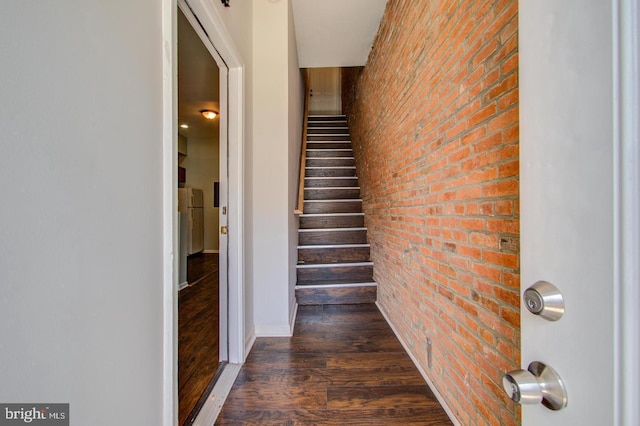 stairs with hardwood / wood-style flooring and brick wall