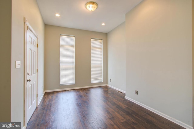 empty room featuring a healthy amount of sunlight and dark hardwood / wood-style flooring