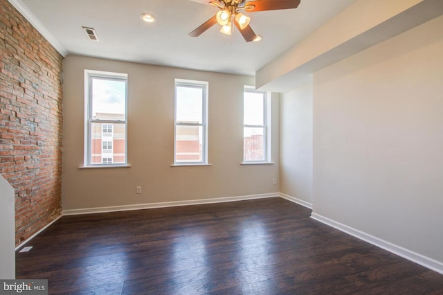 unfurnished room with dark hardwood / wood-style flooring, plenty of natural light, ceiling fan, and brick wall