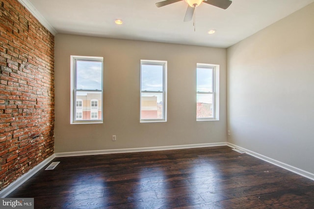 empty room featuring ceiling fan, brick wall, and dark hardwood / wood-style flooring