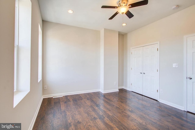 unfurnished bedroom with ceiling fan, dark hardwood / wood-style flooring, and a closet