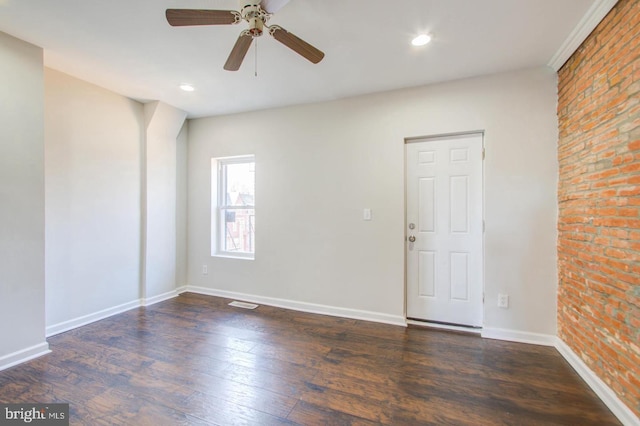 spare room featuring brick wall, dark hardwood / wood-style floors, and ceiling fan