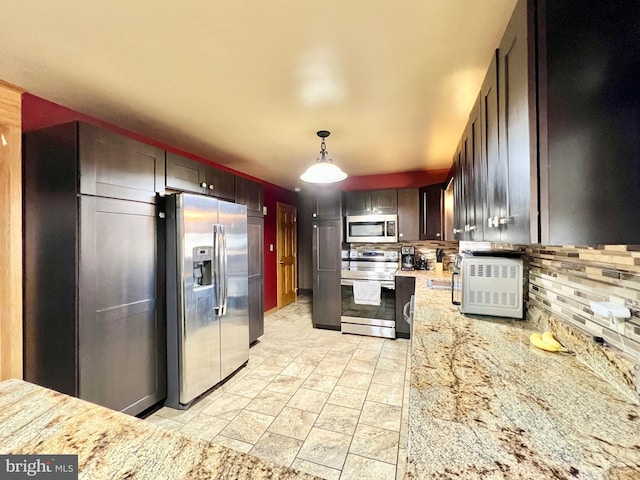 kitchen with pendant lighting, light stone counters, decorative backsplash, and stainless steel appliances