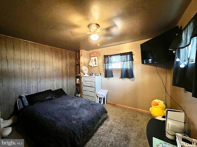 carpeted bedroom featuring ceiling fan and wood walls