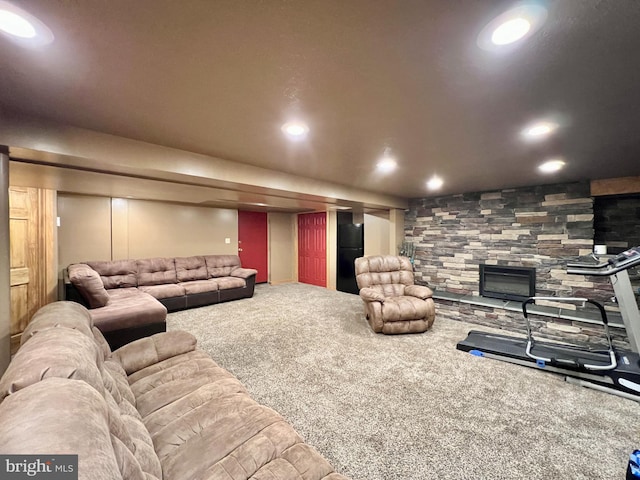 carpeted living room featuring a stone fireplace