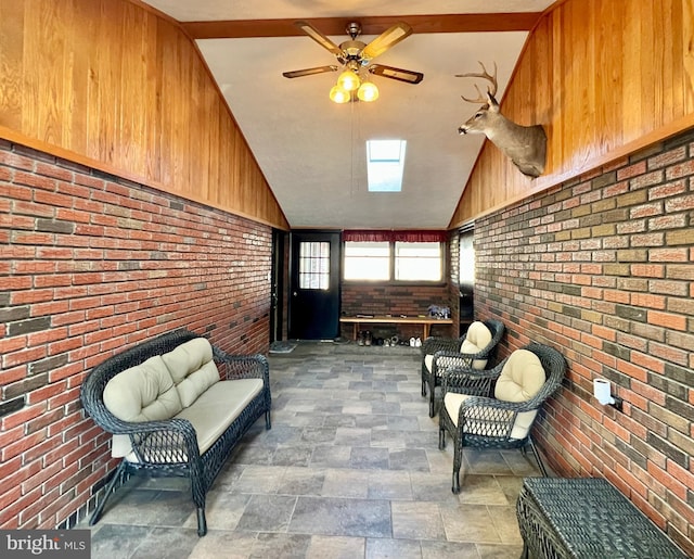 unfurnished room featuring vaulted ceiling, brick wall, and ceiling fan