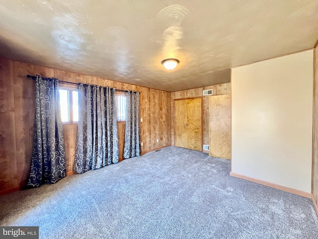 carpeted empty room with wood walls