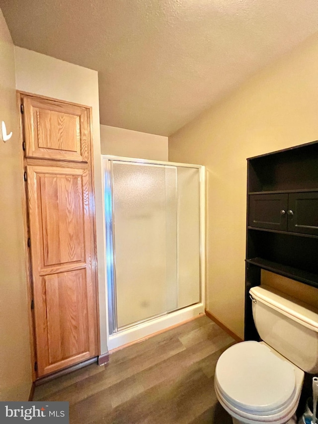 bathroom with walk in shower, wood-type flooring, toilet, and a textured ceiling