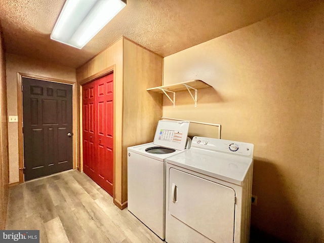 clothes washing area with light hardwood / wood-style flooring and washer and clothes dryer