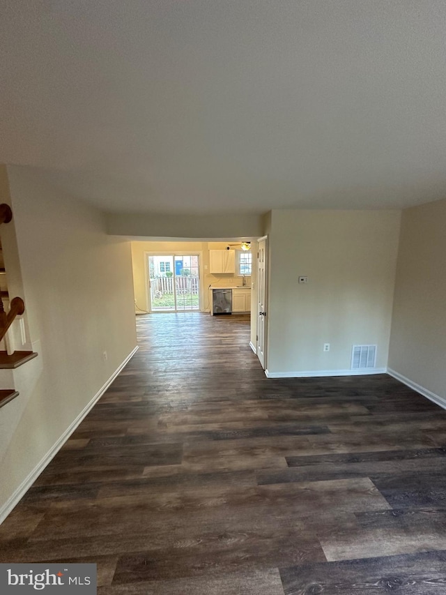 unfurnished living room featuring dark wood-type flooring and sink