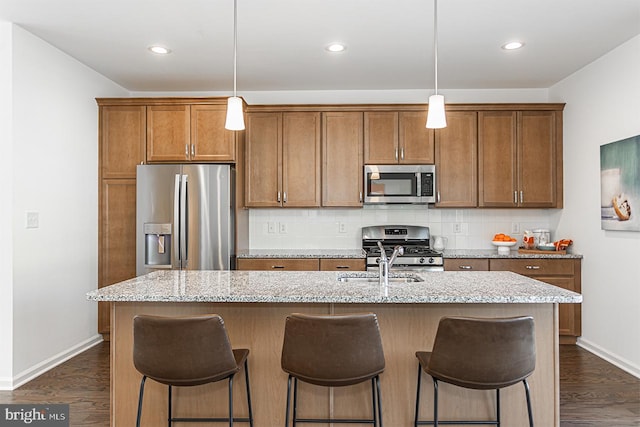 kitchen featuring pendant lighting, stainless steel appliances, and an island with sink